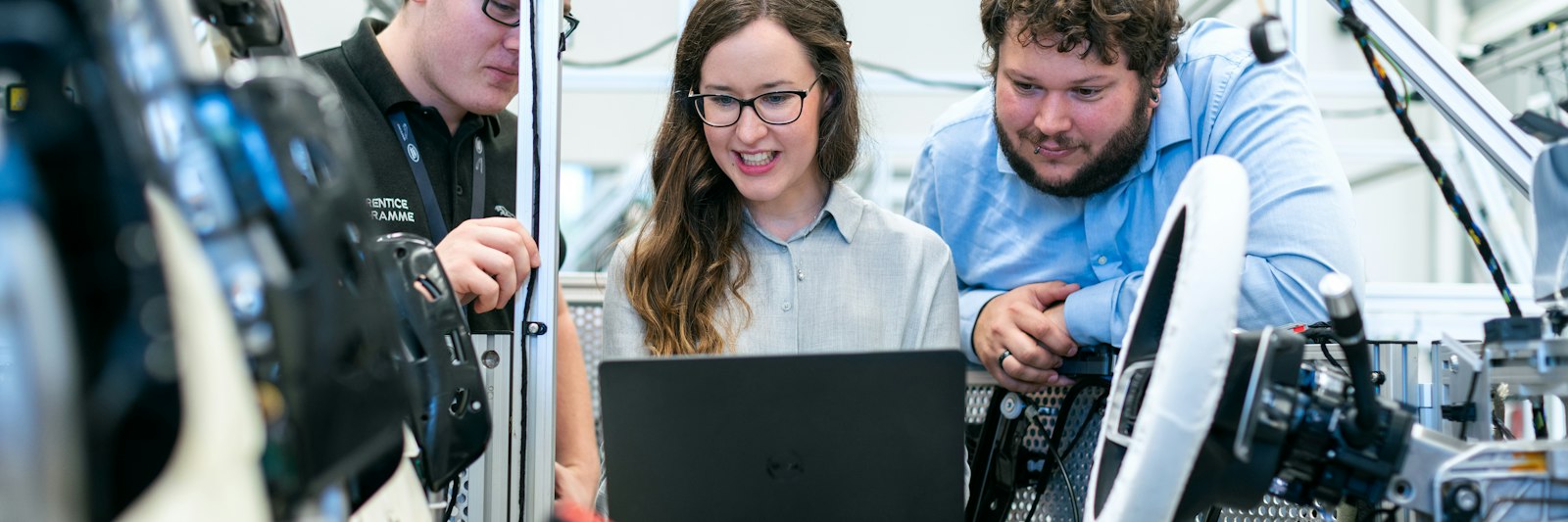 Engineers performing a safety analysis on a laptop in an automotive workspace